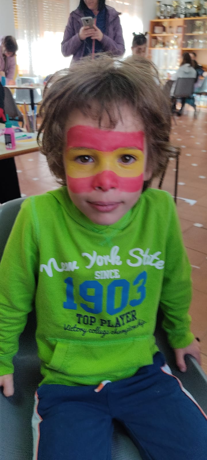 Niño con maquillaje en cara de bandera de España.