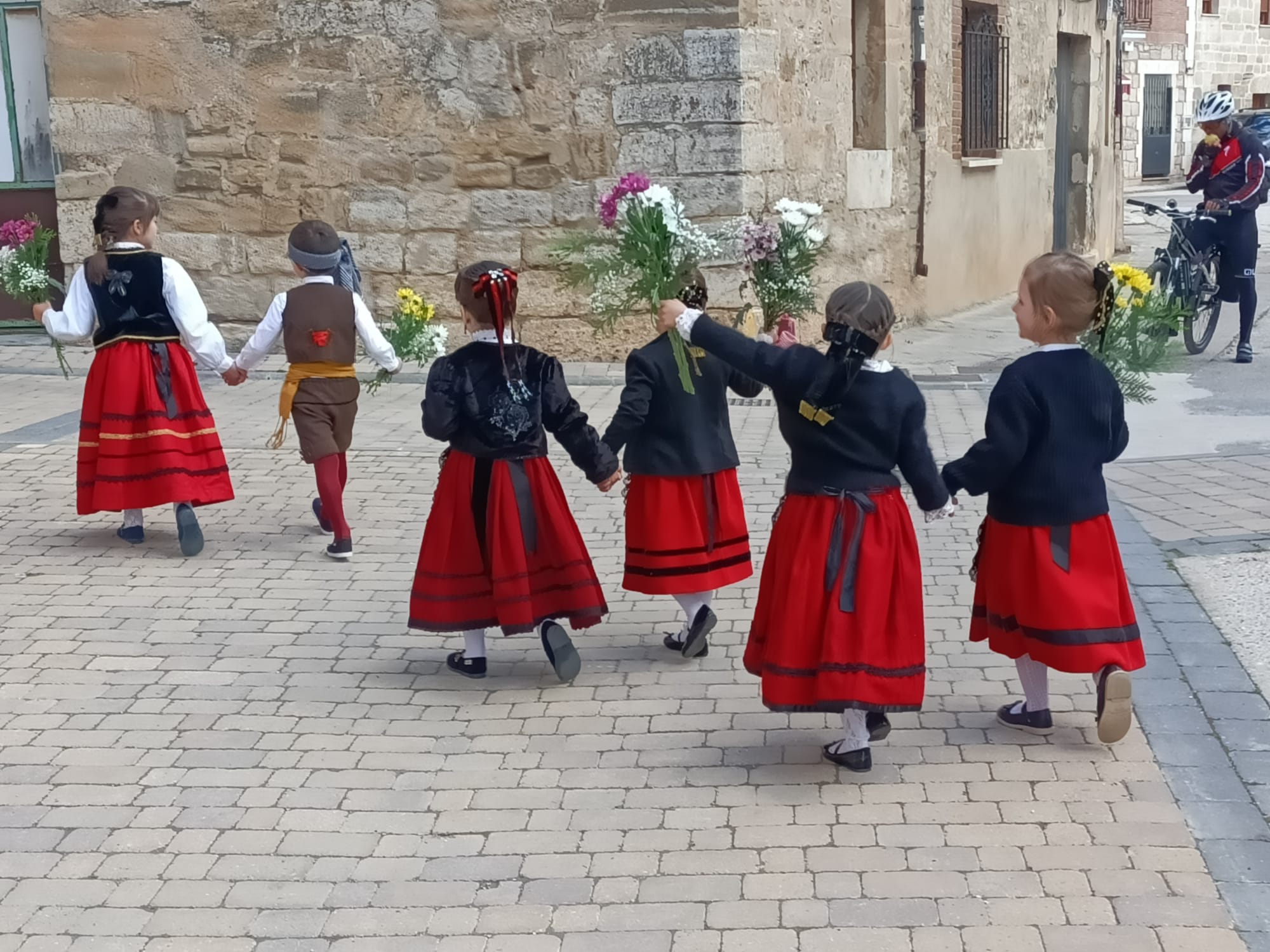 Niños pequeños vestidos con los trajes tradicionales dirigiéndose a la ofrenda floral